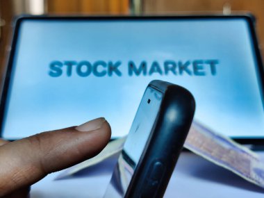 Ekranda borsa metni olan akıllı telefonlu bir el resmi. İş konsepti.