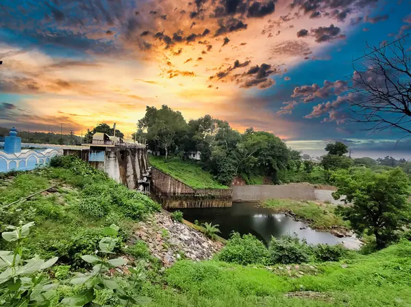 stock image Banswara, Rajasthan, India 9 August 2024: Picture of gates of a dam shot against a beautiful sunset. Green trees in background