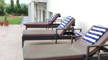 Sawai Madhopur, Hindistan 8 Haziran 2024: Yüzme havuzu, ağaçlar, gün ışığında çekilen sandalyeler. Mavi, havuzu yansıtan şehir mimarisi manzarası ortamı