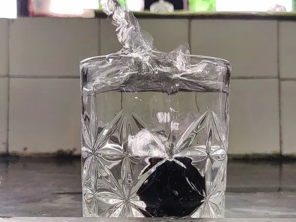 Suyun bulanık bir arkaplanda cam bir çekime sıçraması.