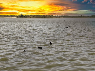 Bulutlu gökyüzü ile gölün üzerinde güzel bir günbatımı resmi. Doğa bileşimi.