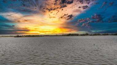 Bulutlu gökyüzü ile gölün üzerinde güzel bir günbatımı resmi. Doğa bileşimi.