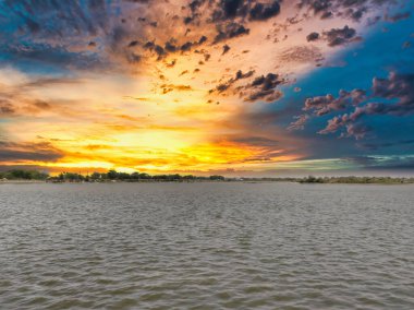 Bulutlu gökyüzü ile gölün üzerinde güzel bir günbatımı resmi. Doğa bileşimi.