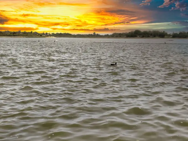 Bulutlu gökyüzü ile gölün üzerinde güzel bir günbatımı resmi. Doğa bileşimi.