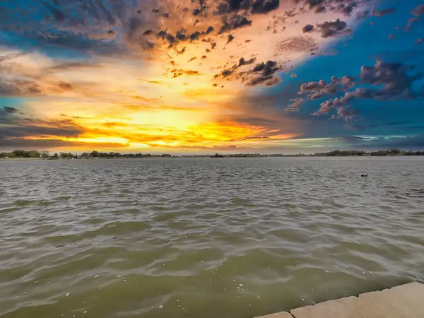 Bulutlu gökyüzü ile gölün üzerinde güzel bir günbatımı resmi. Doğa bileşimi.