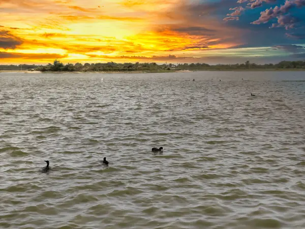 Bulutlu gökyüzü ile gölün üzerinde güzel bir günbatımı resmi. Doğa bileşimi.