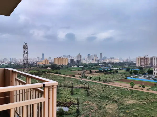 Şehir manzarasının havadan görüntüsü. Arkaplanda bulutlu gökyüzüne karşı tarım arazisi ve binalar