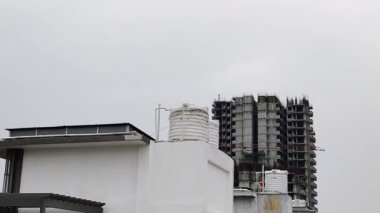 Bulutlu gökyüzüne karşı inşaat halindeki vinçlerle inşaat alanının görüntüsü.