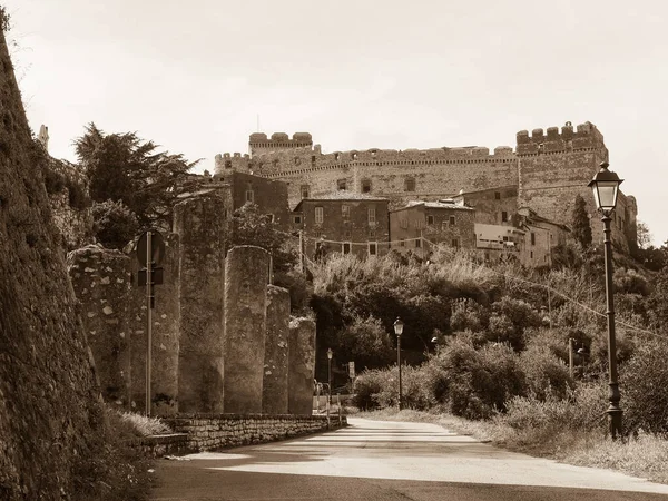 Eski harabe sütunları, ortaçağ evleri ve tepenin üstündeki ünlü Caetani Kalesi manzaralı güzel bir Sermoneta kasabası. Geleneksel İtalyan manzarası. Siyah beyaz sepia tonu fotoğrafçılık.