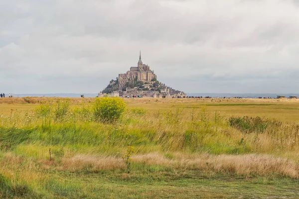 Kayalık Mont-Saint-Michel 'in panoramik manzarası. Birçok turist her gün gelgit adasına güzel manzaralardan geçiyor. Bulutlu ve yağmurlu bir gün. Normandiya, Fransa.
