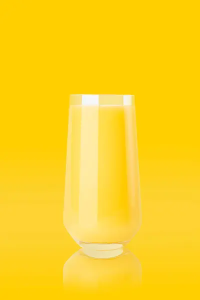 カラフルな黄色の背景 コピースペース 垂直上の反射とガラスの黄色のオレンジジュース ポスター カード デザインのための新鮮な夏の健康的な柑橘類飲料 — ストック写真