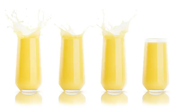 stock image Set of four yellow orange fresh juices in glass with reflection, calm and drops, splashing isolated on white background. Vitamin organic pulppy citrus summer drink with splashes.