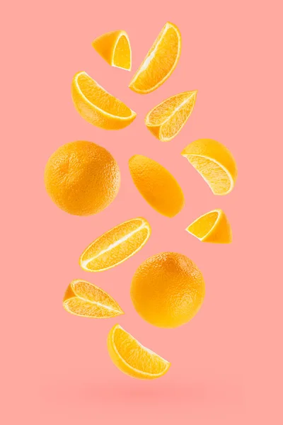 Bright oranges as flow fly or fall as art composition. Whole, half, quarter pieces fruits on pastel pink background with shadow. Tropical fruits for advertising, design, label product, poster, card.