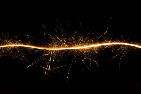 Christmas festive abstract background with burning curved line of sparkler on black background, copy space. New Year decorative glowing stripe of fire for advertising, design, poster, card, flyer.