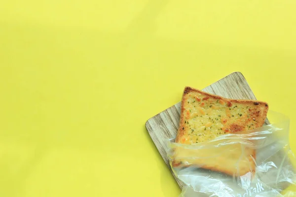 Sarı Arka Planda Tahtanın Üzerinde Sarımsaklı Ekmek — Stok fotoğraf