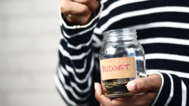 budget text on a saving coins jar on white ,