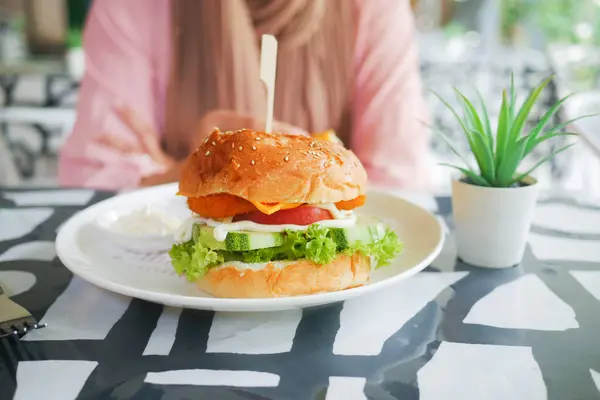 stock image hand holding beef burger on table close up .