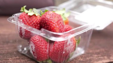  Plastik bir paketten olgun bir kırmızı çilek al. ,