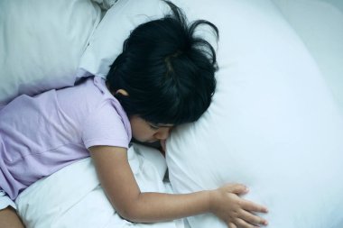 4 yaşında bir kız çocuğu yatakta uyuyor. .