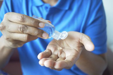 Virüsü önlemek için dezenfektan jel kullanarak genç adamın elini kapat..