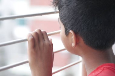 Pencereden bakan üzgün genç çocuk. .