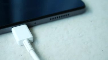 Beyaz arkaplanda kabloyla dijital tableti yükler ,