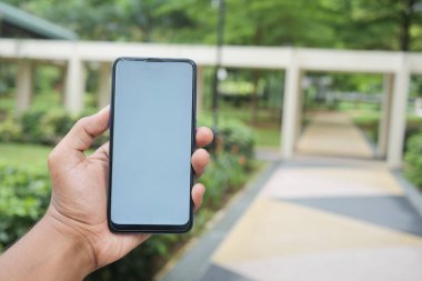 Açık havada akıllı telefon kullanan genç bir adamın dikiz görüntüsü .