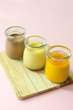  Karamel, çikolata ve mango pudingi pembe arka planda cam bir kavanozda. ,