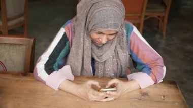 Kafede akıllı telefon kullanan genç Müslüman kadınlar. .