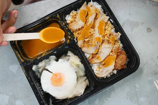 curry chicken and rice in a take away plastic packet on table .