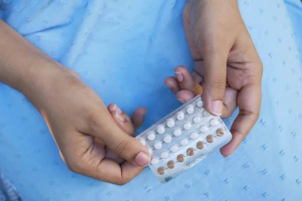 women hand holding birth control pills close up.