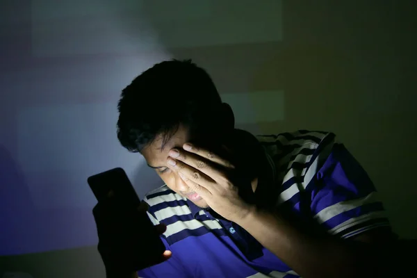 young man on bed using smart phone at night .