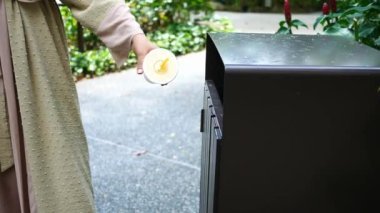 women hand throwing an empty plastic water bottle in the garbage trash or bin,