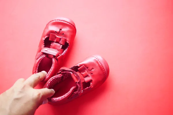 Women Holding Childrens Shoes Red Background — Stock Photo, Image