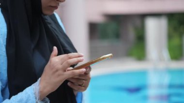 Genç Müslüman kadınlar parkta akıllı telefon kullanıyorlar. .