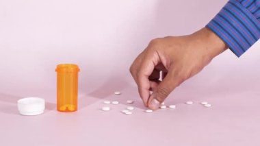  Pembe üzerine beyaz renkli tıbbi haplar dökülüyor. ,