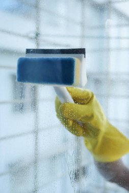 Sarı eldivenler ve cam temizleme için bir tırmık. .