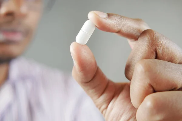 young men holding a single medical pills