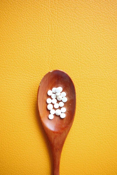 artificial sweetener container on a spoon on orange background .