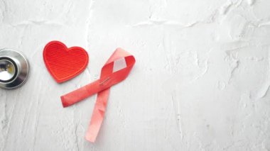 Kırmızı kurdele HIV ve pembe arka planda steteskop...