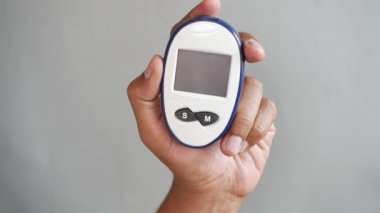 Gri arkaplan üzerinde bir glikoz ölçer tutan erkekler .