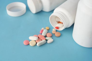 Tıbbi haplar ve kapsül mavi arka plana dökülüyor. .