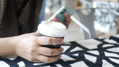  Kadınlar ellerinde akıllı telefon ve kağıt kahve fincanı tutuyorlar. ,