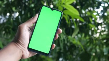 Açık havada akıllı telefon kullanan genç bir adamın dikiz görüntüsü .