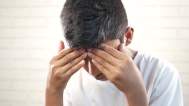 sad teenage boy covering his face sitting on sofa ,