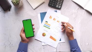 holding smart phone and analyzing financial data .