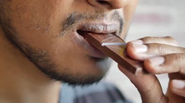 Genç adam siyah çikolata yiyor. .