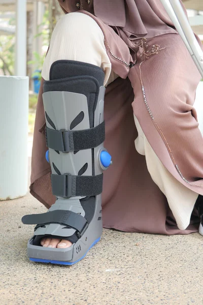 women broken feet with a grey plastic boot ankle brace injury protecting boot,