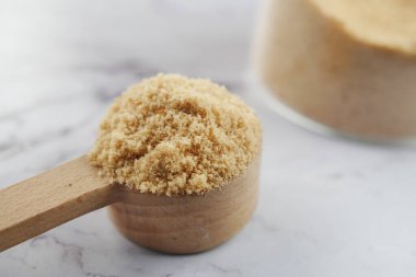 coconut sugar on a wooden spoon on white .