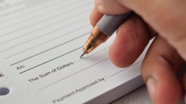  A man writes payment due in a paper form .